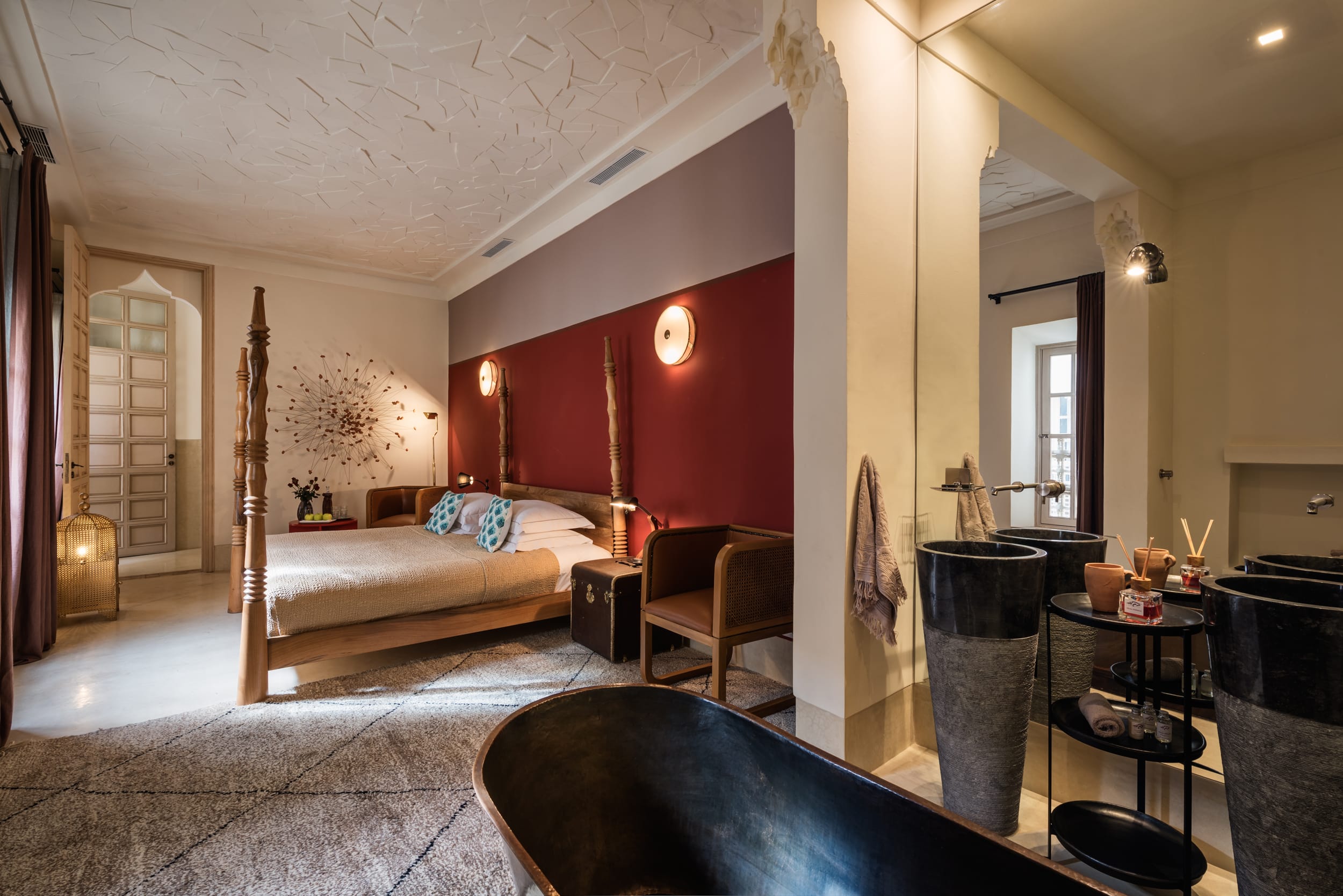 Contemporary suite with a four-poster bed, red accent wall and open bathroom at 72 Marrakech