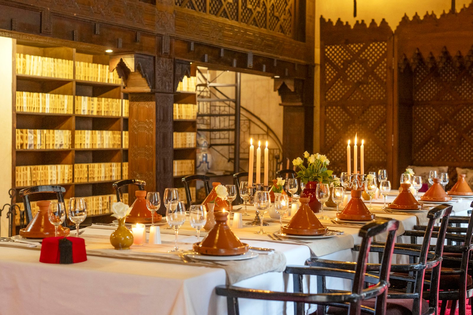 Salle à manger aux chandelles devant un mur de livres à Almaha Marrakech