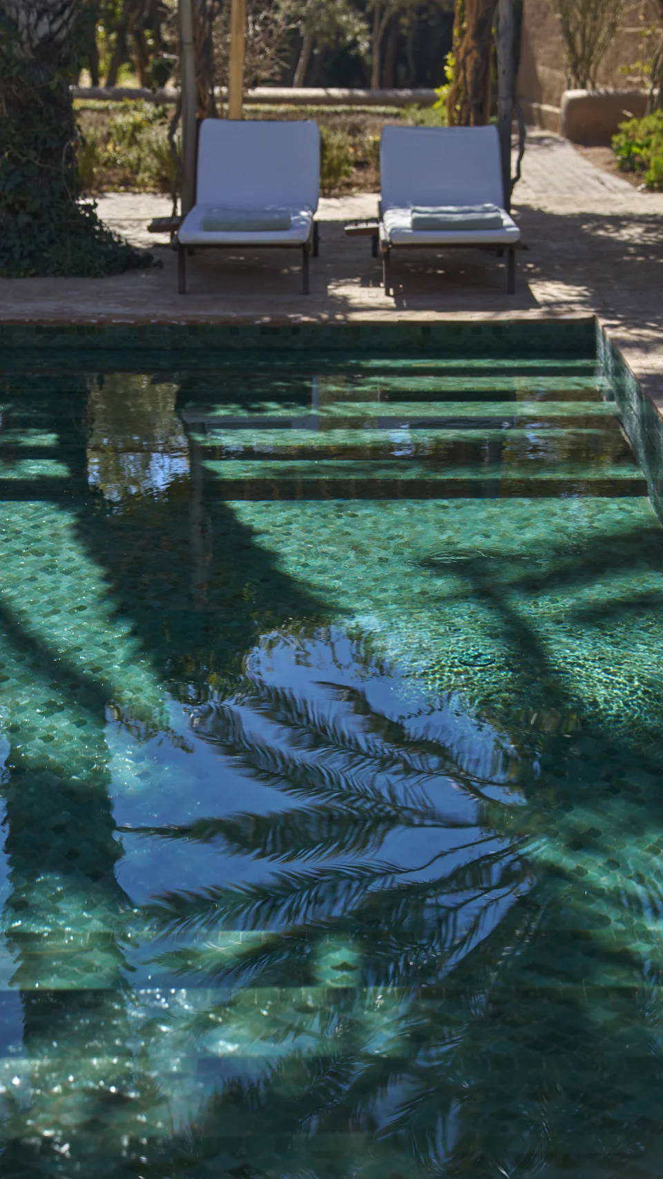 Marches de piscine, reflets et transats dans le jardin de Dar Ahlam