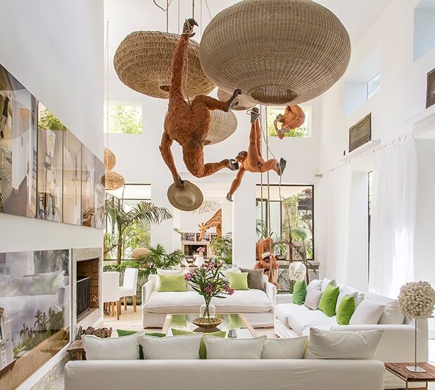 Salon blanc en double hauteur avec des sculptures d’orangs-outans suspendues aux luminaires tressés
