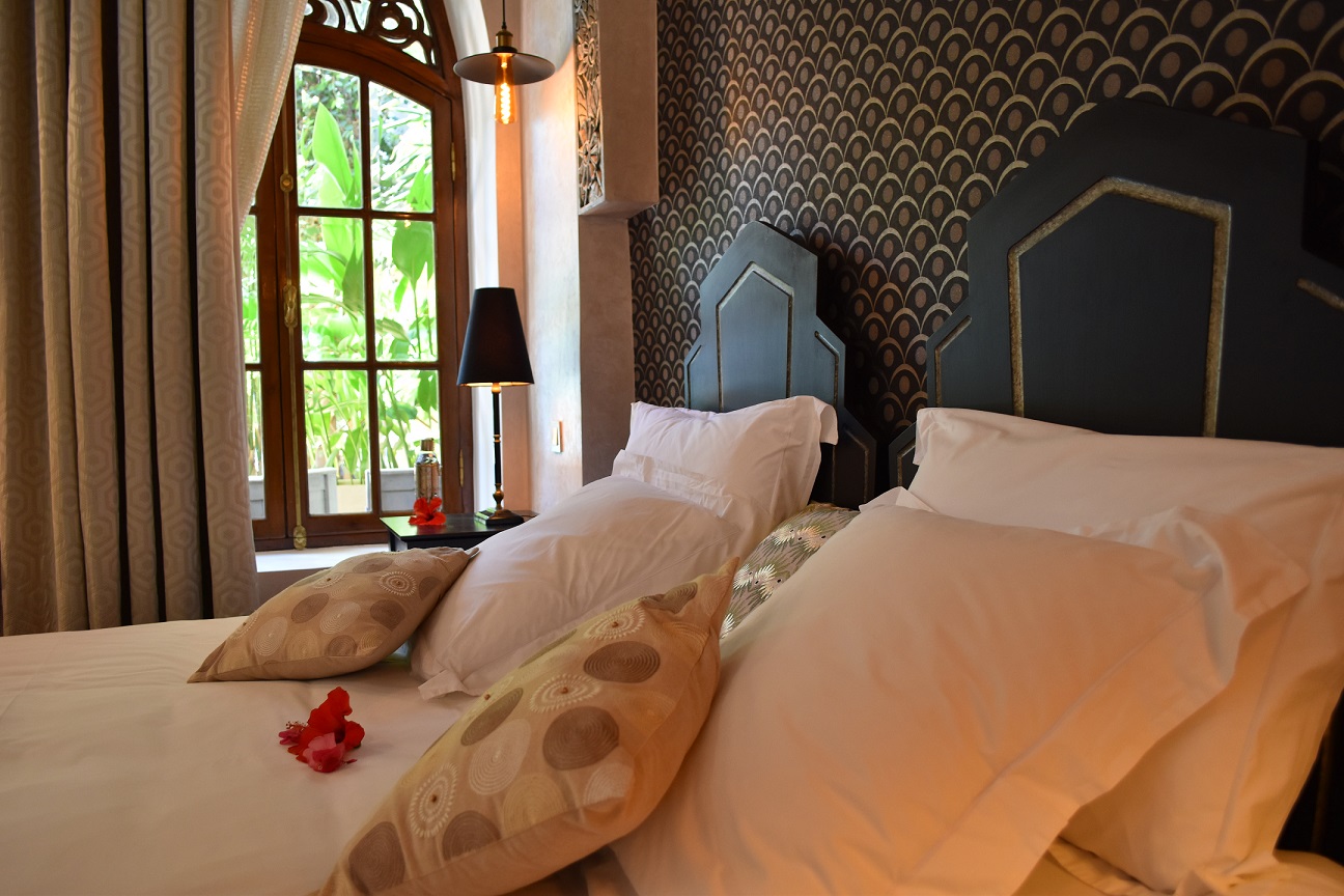 Chambre de suite avec têtes de lit géométriques sombres et fenêtre sur le jardin