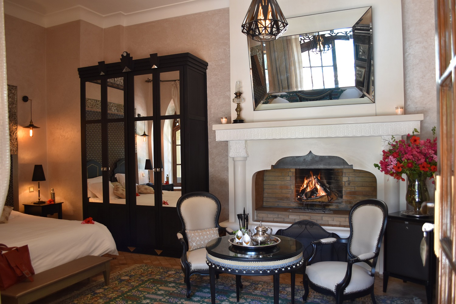 Intérieur spacieux d’une suite avec cheminée, table ronde et armoire sculptée