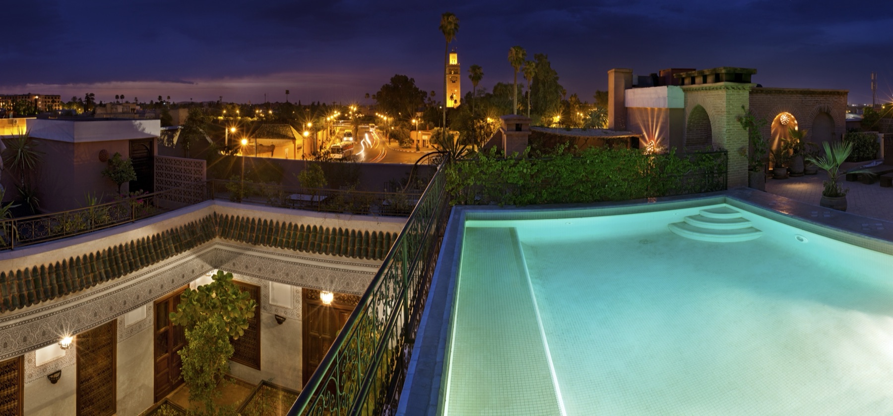Rooftop pool at dusk with the Koutoubia on the Marrakech skyline