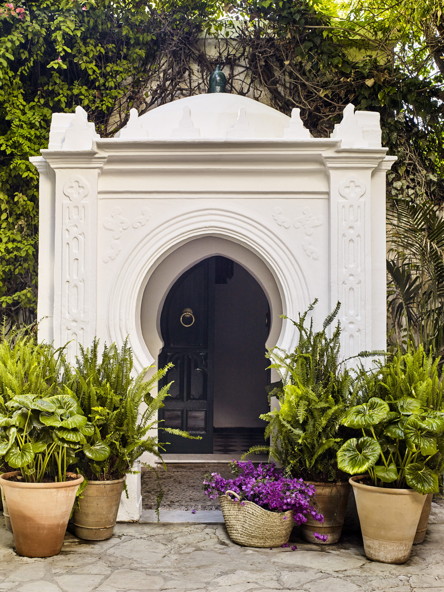White courtyard entrance surrounded by the gardens of Villa Mabrouka in Tangier