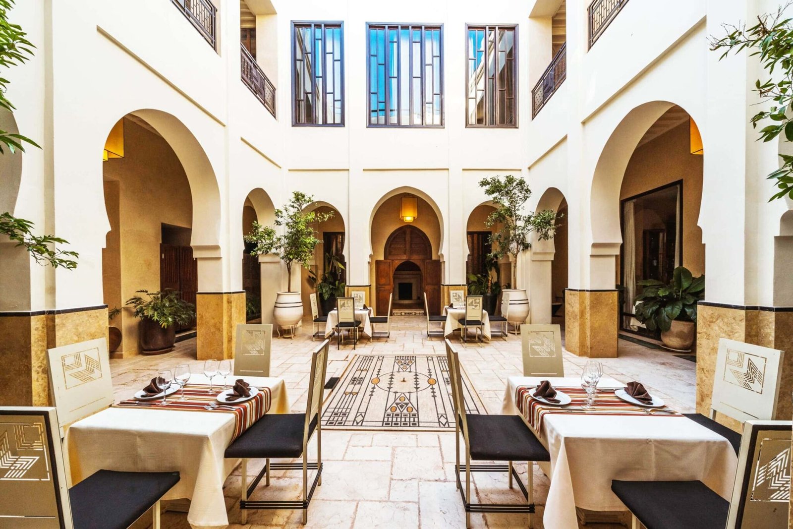 Art Deco dining tables beneath the arches of Villa Makassar’s courtyard